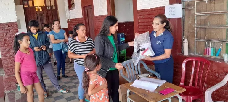 La directora de la Escuela Monseñor Ángel Nicolás Acha,  hace entrega del kit escolar a los padres de familia.