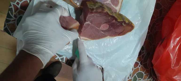 Un funcionario de Senacsa corta los pedazos de carne porcina que fueron traídos desde España por una pareja de paraguayos y fue confiscada.