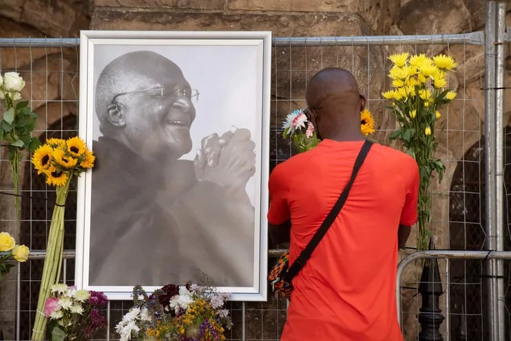 Una persona ora ante la foto del arzobispo anglicano de Ciudad del Cabo, Desmond Tutu.