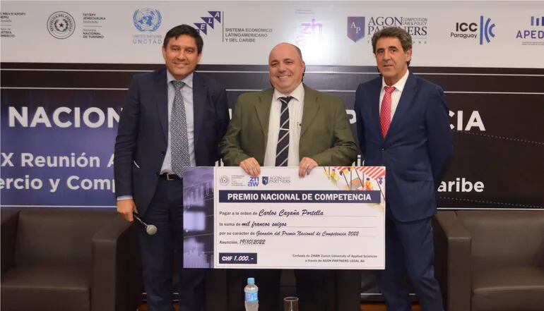 Carlos Cazaña Portella (centro), el ganador del "Premio Nacional de la Competencia", recibió mil francos. La distinción recibió  de Rolando Díaz, presidente de Conacom (d), y Juan Luis Crucelegui, Jefe de Fortalecimiento de Capacidades de UNCTAD.