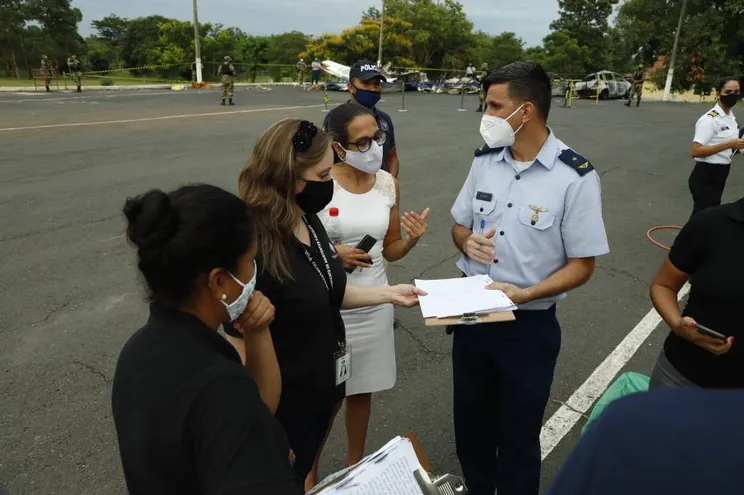 La fiscala Fátima Villasboa (de blanco) se hizo presente esta tarde el predio de la Fuerza Aérea para la primeras diligencias. En la foto, conversa con un efectivo militar, rodeada de sus ayudantes.