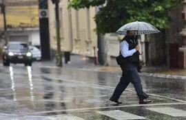Un ciudadano cruza la calle en Asunción, que está cubierta de agua, con una sombrilla para protegerse de las precipitaciones.