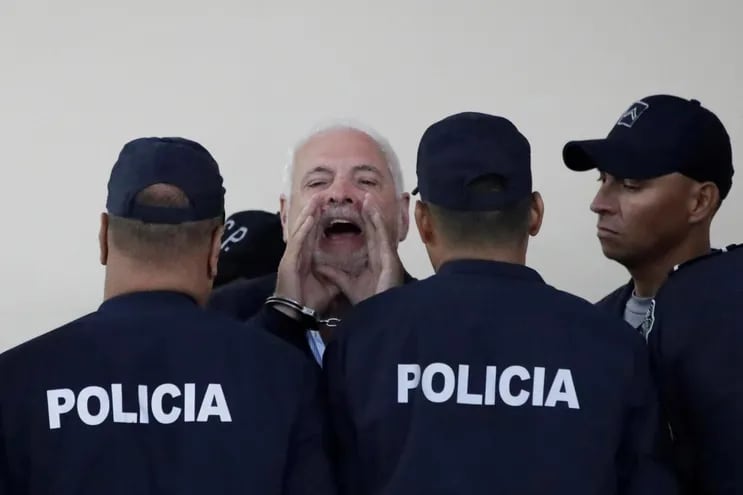 El expresidente de Panamá (c) aparece esposado y custodiado por varios agentes panameños. Afronta una causa que podría enviarlo a prisión por unos 12 años.