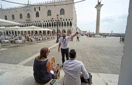 Una agente alerta a los turistas sobre la llegada de una marea alta, en la zona de la plaza de San Marco, en Venecia, Italia.