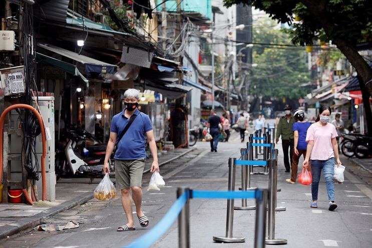 Separadas en carriles, como medida de prevención contra el Covid, las personas caminan por el mercado Hang Be de Hanoi, Vietnam.