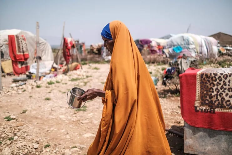 Yurub Abdi Jama, de 35 años y madre de 8 hijos, camina sosteniendo una taza en un asentamiento informal de desplazados internos en las afueras de la ciudad de Hargeisa, Somalilandia.