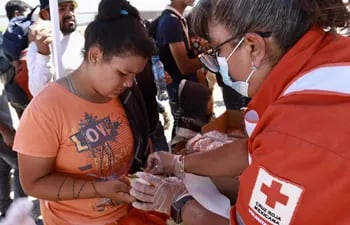 Una voluntaria de la Cruz Roja reparte alimentos a migrantes hoy, en Ciudad Juárez, Chihuahua (México).
