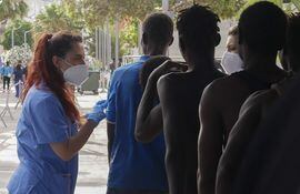 Dos sanitarias atienden a decenas de inmigrantes han entrado este viernes en Melilla tras romper la puerta de acceso al paso fronterizo de Barrio Chino y saltar por encima de su tejado que separa la ciudad autónoma de Marruecos.