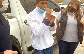 Esposado, el indígena Jonny Paredes Gauto toma agua, antes de ser trasladado a su lugar de reclusión. La Fiscalía lo imputó ayer y pide prisión para el mismo.