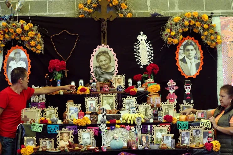 Marcelo Romero (i), acompañado de Concepción Romero (d), dan los últimos detalles a una ofrenda por sus familiares fallecidos por la Covid-19, en Ciudad de México (México).