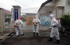 Volunarios de la Cruz Roja desinfectan la entrada de un colegio en Yakarta, ante el incremento de contagios de covid-19.
