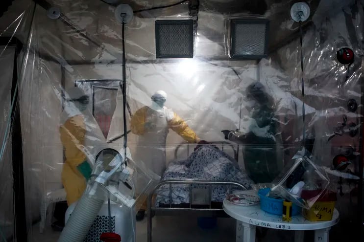 En esta foto de archivo tomada el 15 de agosto de 2018, tres trabajadores médicos controlan a un paciente con ébola en un Biosecure Emergency Care Unite (CUBE).