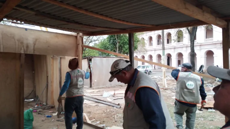 Varios trabajadores municipales proceden a desarmar las casas precarias de terciada y chapa que están frente a El Cabildo. (Fuente Twitter).