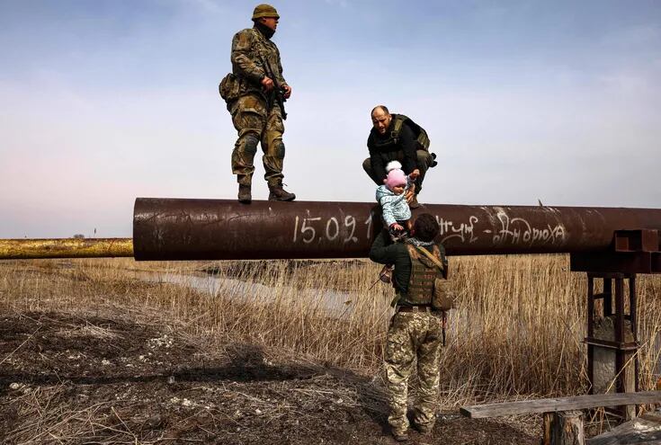 Miembros de las fuerzas ucranianas asisten a un padre y su bebé en las afueras de Kiev. (AFP)