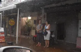 Dos mujeres se resguardan de la lluvia en Asunción.