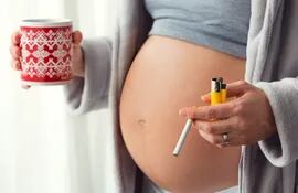 Mujer embarazada fumando y tomando café