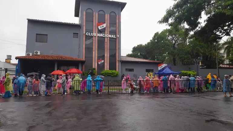 Bajo la lluvia esperan la apertura de portones para el ingreso al concierto de Karol G en Paraguay.