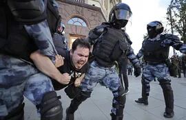 Policías antidisturbios llevan detenido a uno de los manifestantes de la protesta en Moscú.