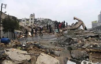 La gente se reúne alrededor de los edificios derrumbados mientras los equipos de rescate buscan sobrevivientes después de un terremoto en la ciudad siria de Alepo, controlada por el gobierno.