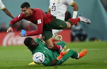 Cristiano Ronaldo choca con el arquero ghanés Lawrence Ati Zigi, durante el partido de ayer.