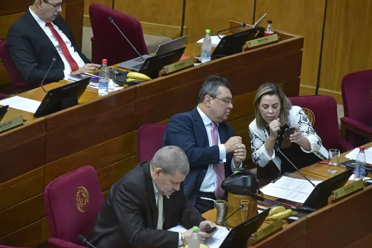 La senadora Lizarella Valiente muestra su celular al senador Gustavo Leite, también del cartismo, en la sala de sesiones del Senado.