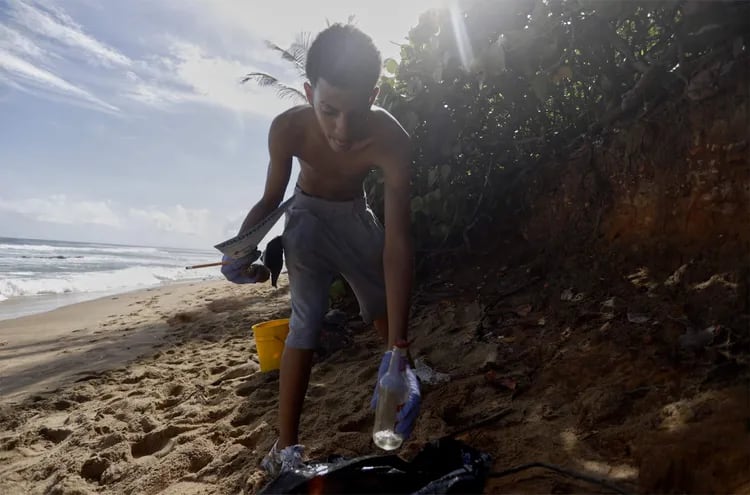 Un voluntario recolectan basuras en una playa en San juan (Puerto Rico).