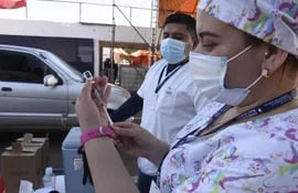 Una funcionaria de blanco prepara una de las dosis de la vacuna de Pfizer en el autódromo Rubén Dumot, exAratirí.