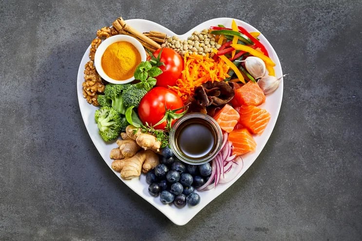 Plato en forma de corazón con diferentes tipos de alimentos saludables.