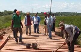 Funcionarios del MOPC y la Municipalidad de San José trabajan en el cambio de las maderas de la pasarela sobre el arroyo Yate´i