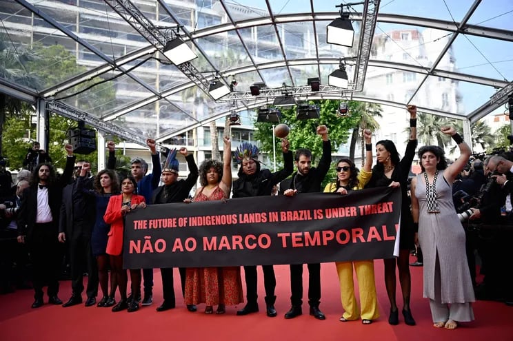 Miembros de la película “Crowra” protestando detrás de una pancarta “El futuro de las tierras indigenas en Brasil está bajo amenaza” en la alfombra roja del Festival de Cine de Cannes