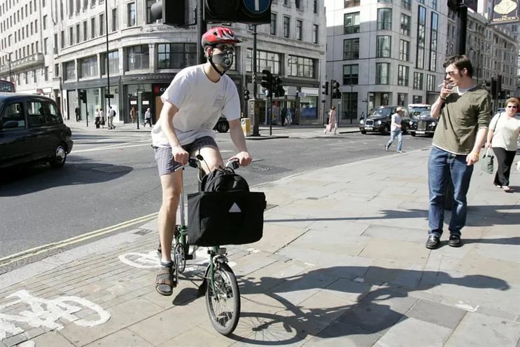 Un londinense se dirige a trabajar en una bicicleta Brompton, protegido con una mascarilla, en la cara en Londres, Reino Unido.
