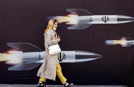 Una mujer camina frente a un mural con imágenes de misiles en Teherán, Irán, este viernes.