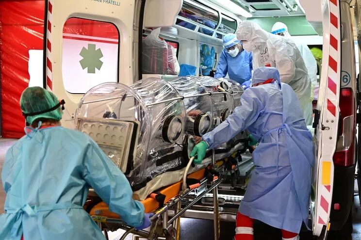 Trabajadores médicos transportan a un paciente con covid-19 en Garbagnate Milanaise, Italia.