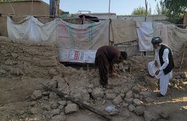 Vecinos de la localidad de Harnai, Pakistán, recogen escombros de una vivienda parcialmente derrumbada.
