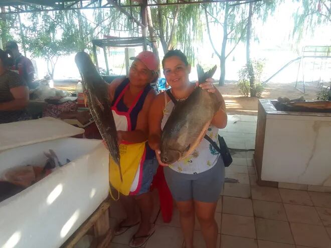 Dos comerciantes de Remanso muestran un pescado surubí y un pacú, que ofrecen por Semana Santa.