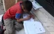Un niño completa sus tareas en una vereda del centro asunceno. El 76% de los estudiantes paraguayos no tiene acceso a tecnología para estudiar, según el MEC.