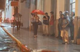 Imagen ilustrativa: lluvia y gente esperando algún bus.