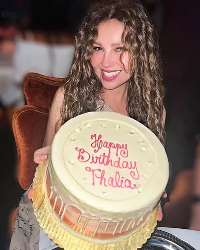 Thalía posando feliz con su torta de cumpleaños.