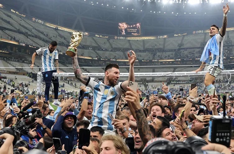 Lionel Messi de Argentina (C) levanta el trofeo mientras celebra con sus compañeros y fanáticos ganar la final de la Copa Mundial de la FIFA 2022 entre Argentina y Francia en el estadio Lusail, Lusail, Qatar, el 18 de diciembre de 2022.