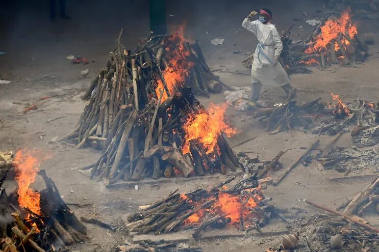 Un voluntario camina entre las piras donde se queman los cadáveres de personas que murieron por coronavirus en un improvisado crematorio al aire libre en Nueva Delhi, India.