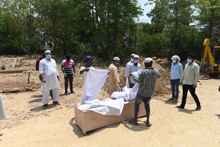 Familiares y amigos preparan el ataúd de una persona que murió a causa del coronavirus, en Nueva Delhi, India.