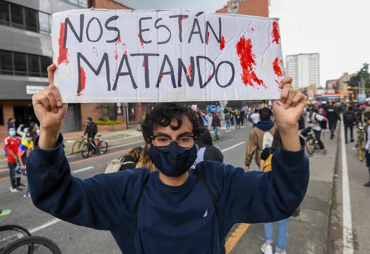 A demonstrator holds a sign reading 'They are killing us' during a protest against a tax reform proposed by Colombian President Ivan Duque's government in Bogota, on May 4, 2021. - The international community on Tuesday decried what the UN described as an 'excessive use of force' by security officers in Colombia after official data showed 19 people were killed and 846 injured during days of anti-government protests. (Photo by Juan BARRETO / AFP)