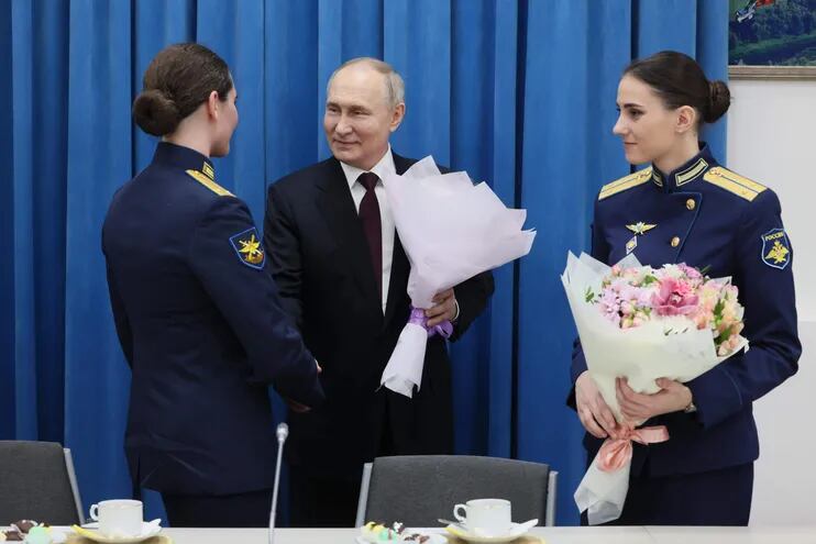 El presidente de Rusia, Vladimir Putin (C), saluda a las soldados tras su graduación en la academia de pilotos ruso y en ocasión del Día Internacional de la Mujer.