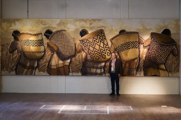 Koki Ruíz posa frente a parte del mural "La recolección de los frutos" que estará en el pabellón de Paraguay en la Exposición Universal de Dubái.