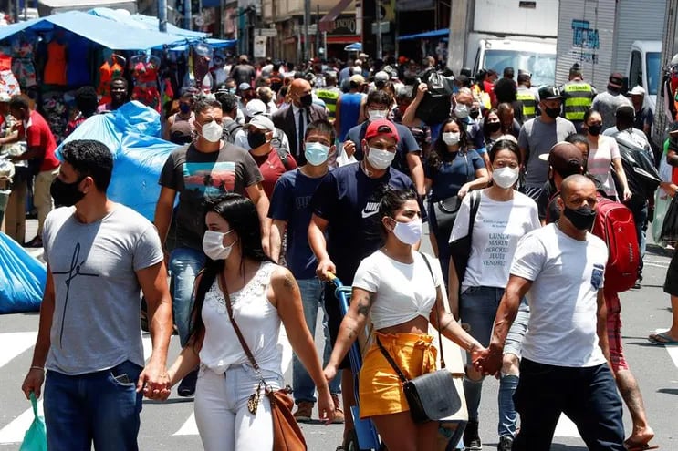 Decenas de personas caminan en una concurrida vía comercial en el centro de Sao Paulo (Brasil).
