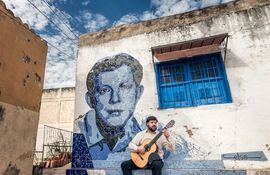 El guitarrista Javier Acosta Giangreco junto al mural de José Asunción Flores. El músico presentará hoy el documental "Medio siglo sin Flores" en la Manzana de la Rivera.