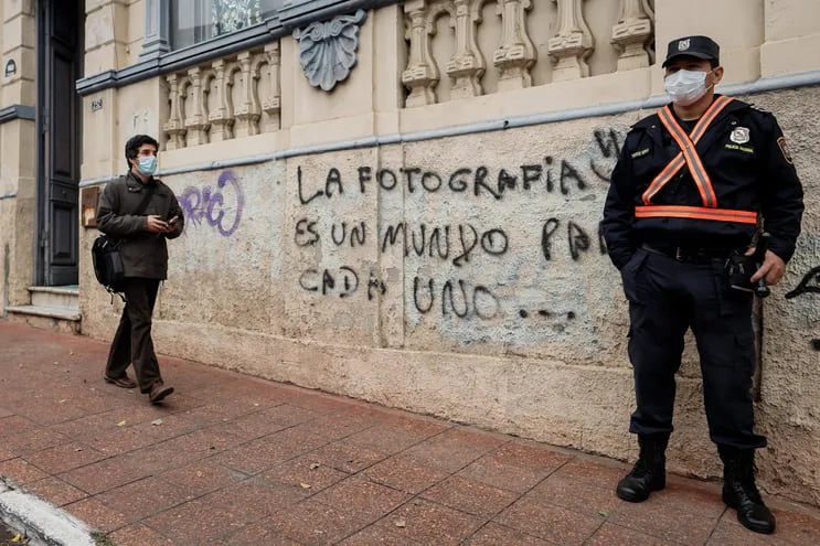Un policía hace guardia junto a un grafiti alusivo a la fotografía, en Asunción.