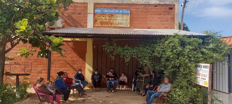 Vecinos sentados frente al comedor Chiquitunga de Coronel Oviedo, para exigir la reactivación del local.