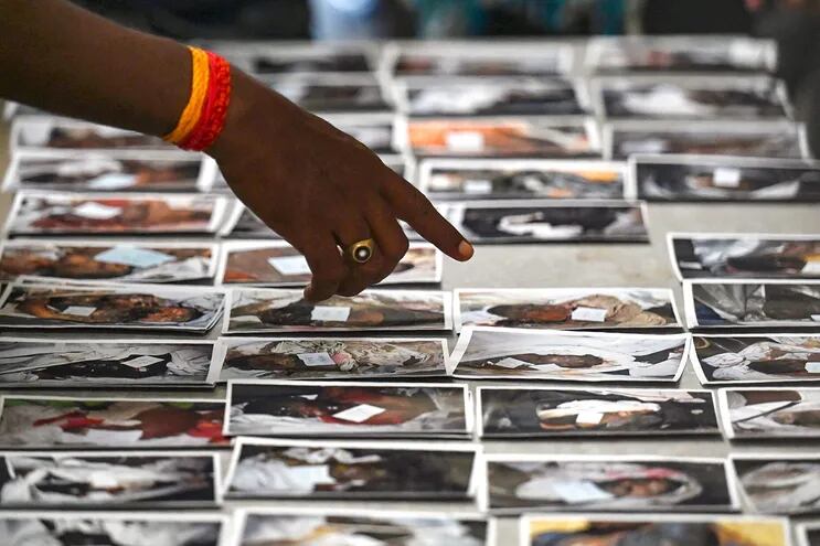 Un familiar mira fotografías de las víctimas del accidente de tren en la India.
