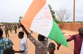 Partidarios del Consejo Nacional para la Salvaguardia de la Patria de Níger ondean la bandera mientras se reúnen para una manifestación en Niamey.